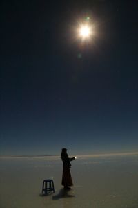 Silhouette man standing in sea against sky