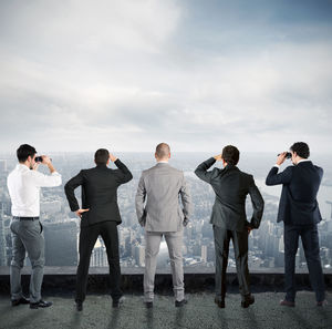 Rear view of people standing against sky