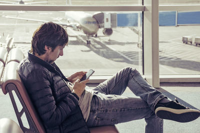 Side view of man using mobile phone at airport