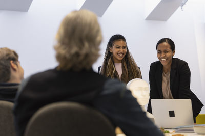 Business people discussing robot voice assistant during meeting