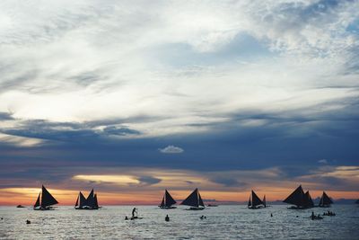 Boats sailing on sea against sky during sunset