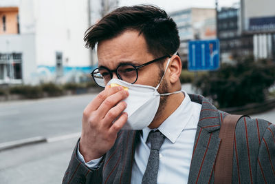 Business man standing on city street with protective face mask.