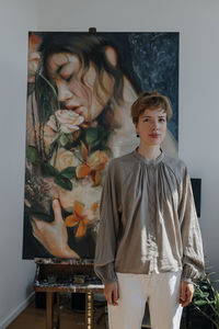 Confident female artist standing against painting in art studio