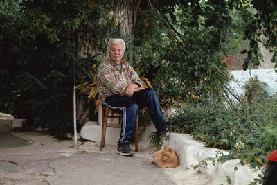 Woman with dog sitting on chair against plants