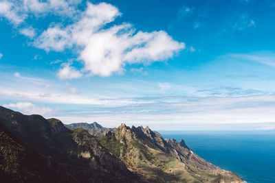 Scenic view of sea and mountains against blue sky