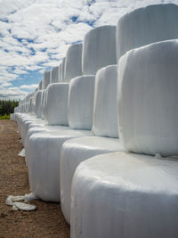 Close-up of white seats on field against sky