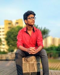 Young man looking away while sitting outdoors