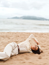 Low section of woman relaxing at sandy beach