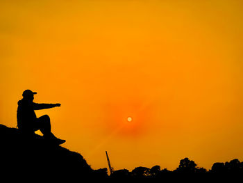 Silhouette man standing against orange sky