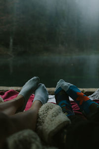 Low section of women relaxing by lake