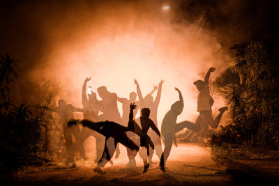 Digital composite image of people jumping over street in foggy weather at night