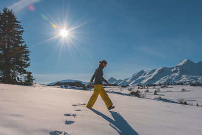 A full-body shot of a young caucasian woman walking in the french alps mountains