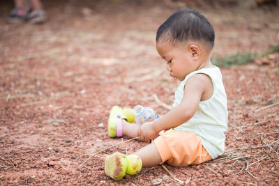 Side view of cute baby boy sitting on land