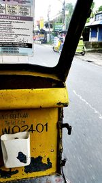 Close-up of yellow sign on road in city