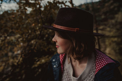 Close-up portrait of young woman standing against trees