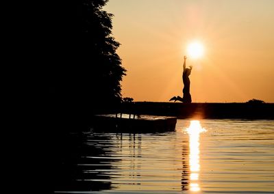 Silhouette boat in lake against sky during sunset