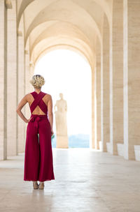 Rear view of woman in red dress standing in corridor