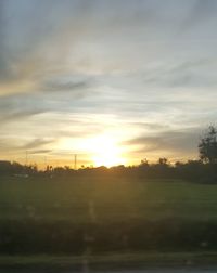 Silhouette trees on field against sky during sunset