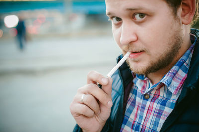 Close-up portrait of man smoking cigarette in city