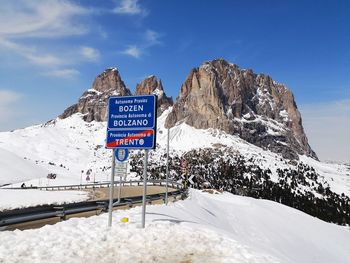 Information sign on snowcapped mountain against sky