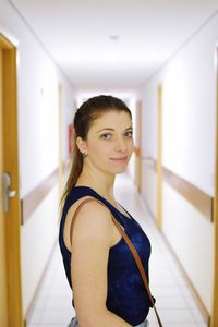 Side view portrait of smiling young woman standing in corridor