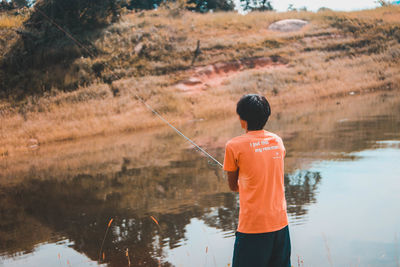 Rear view of boy fishing in lake