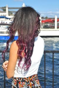 Rear view of woman with purple hair standing in pier during sunny day