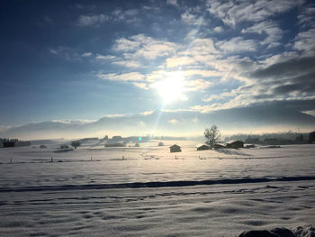 Scenic view of snow covered land against sky during sunset