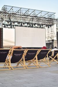 Chairs on table in city against sky