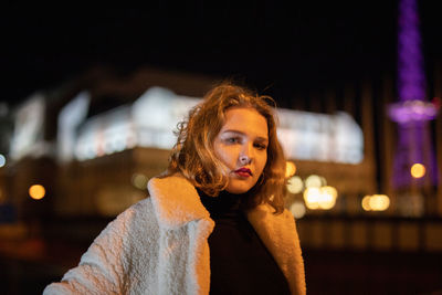 Portrait of young woman standing outdoors at night