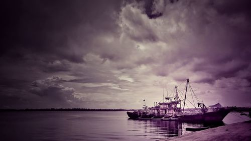 Sailboats in sea against storm clouds