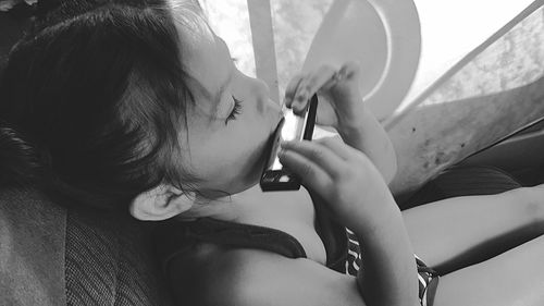 Girl playing harmonica while sitting on chair at home