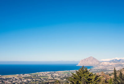 Scenic view of sea and mountains against clear blue sky