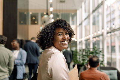 Side view portrait of smiling female entrepreneur with curly hair at convention center