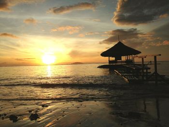 Lifeguard hut on beach against sky during sunset