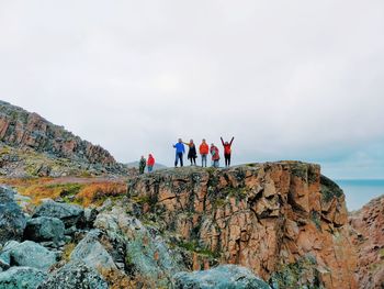 Rear view of people on rock against sky