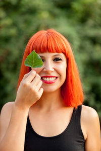 Portrait of smiling woman holding leaf outdoors