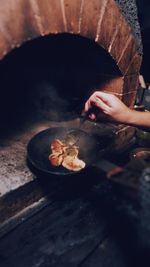 Person holding meat on barbecue grill