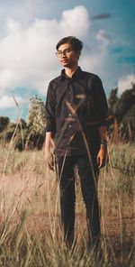 Young man standing on field against sky