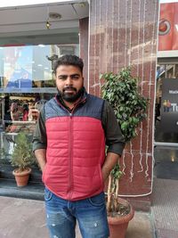 Portrait of young man standing on potted plant