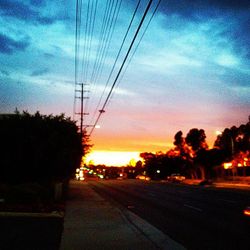 Electricity pylons on road at sunset