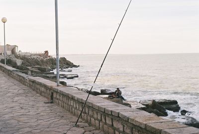 Fishing rod on promenade against sky