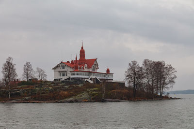 View of building by river against cloudy sky