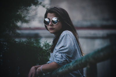 Portrait of teenage girl wearing sunglasses while standing by railing