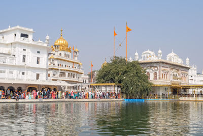 Buildings by river against clear sky