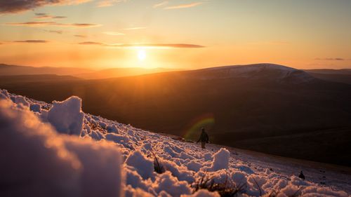 Scenic view of snowcapped mountains against sky during sunset