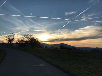 Road amidst silhouette landscape against sky during sunset