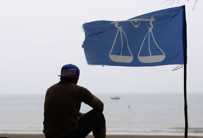 Rear view of man standing at beach against clear sky