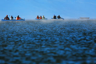 People in kayaks against sky