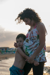 Pregnant mother and son standing on beach